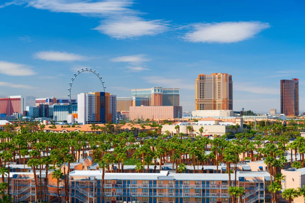 De skyline van Las Vegas met het High Roller reuzenrad en verschillende hotels boven een rij palmbomen