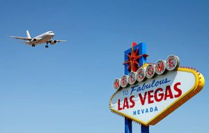 Vliegtuig nadert de landingsbaan boven het Welcome to Fabulous Las Vegas bord tegen een strakblauwe lucht