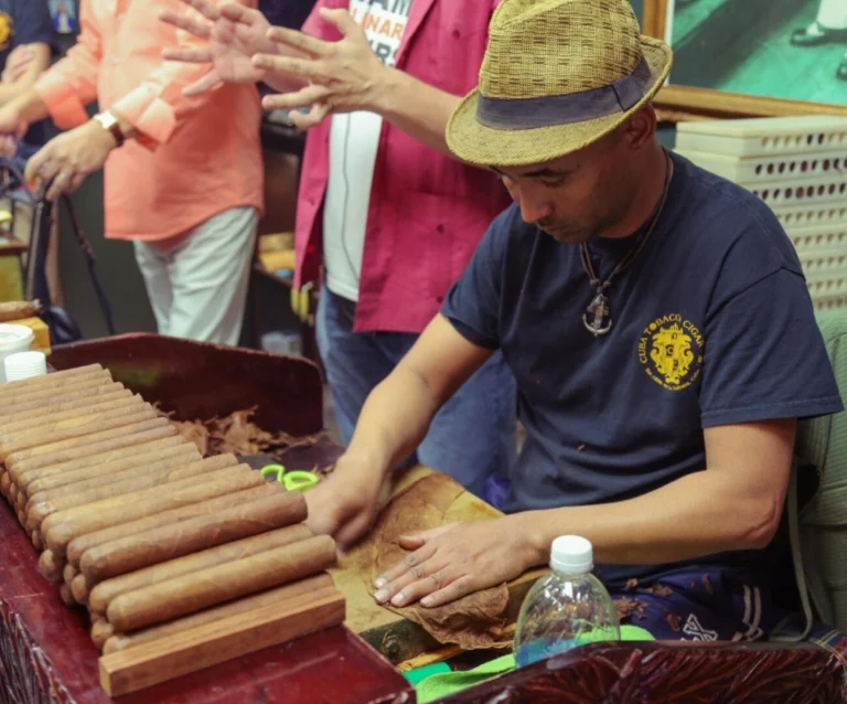 Een man met strohoed rolt met de hand sigaren op een houten werkbank in een sigarenwinkel in Little Havana