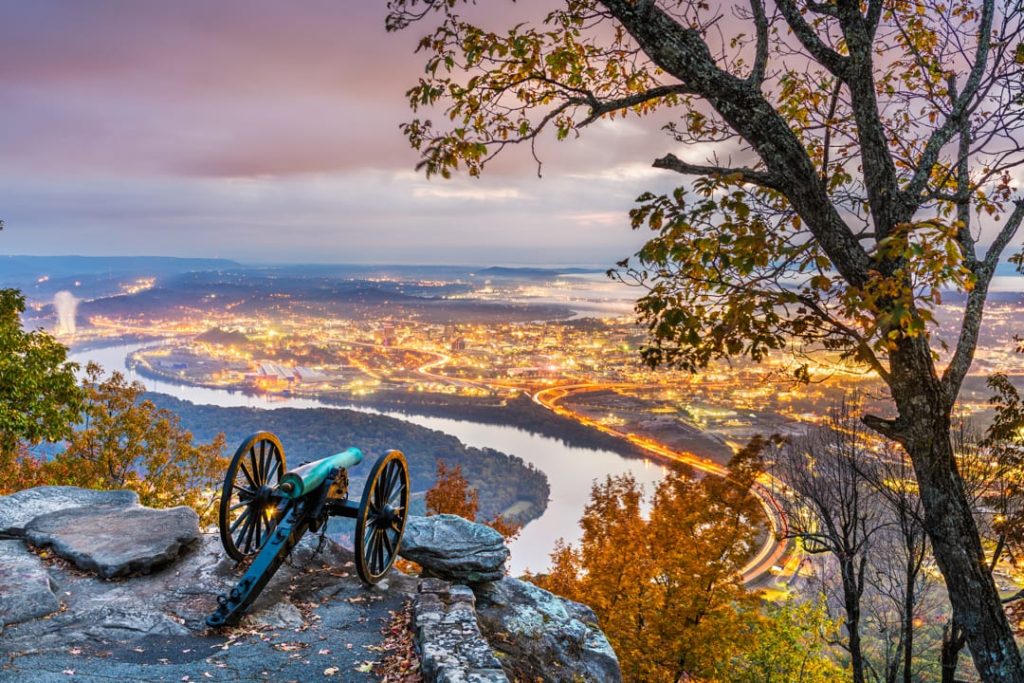 Historisch kanon op een rotsrichel in Point Park, met uitzicht op de verlichte stad Chattanooga en de rivier bij schemering