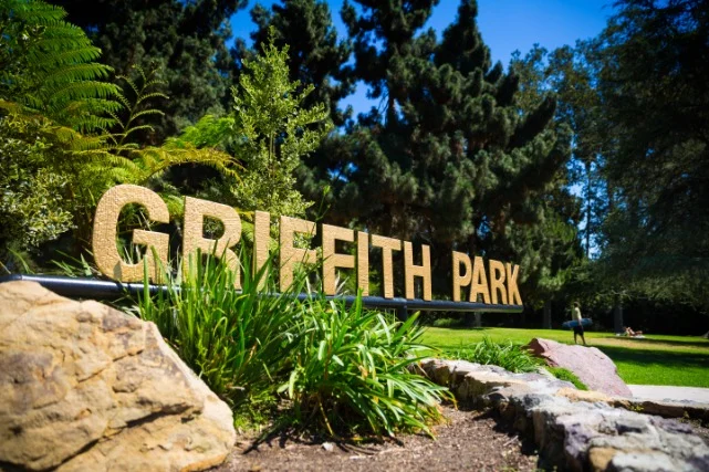 Gouden letters Griffith Park tussen rotsen en groen met bomen en gras op de achtergrond