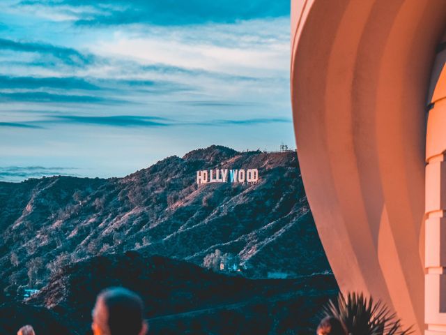 Uitzicht op het Hollywood Sign op een heuvel in de verte, gezien langs de ronde gevel van het Griffith Observatory bij avondlicht