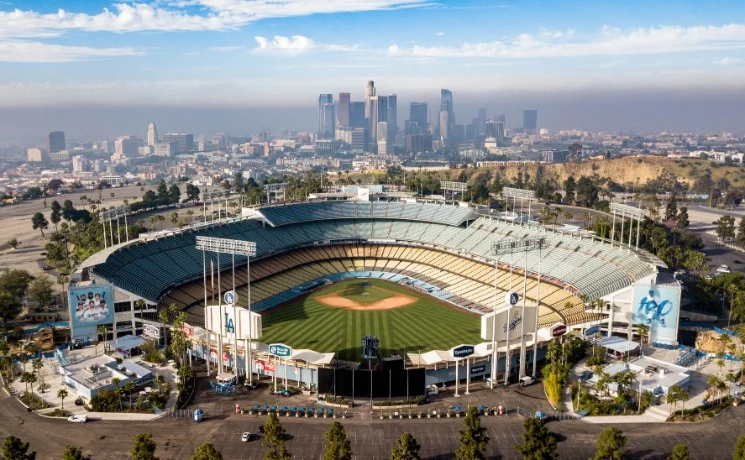 Luchtfoto van het honkbalstadion Dodger Stadium met groen veld en tribunes en de wolkenkrabbers van Los Angeles op de achtergrond