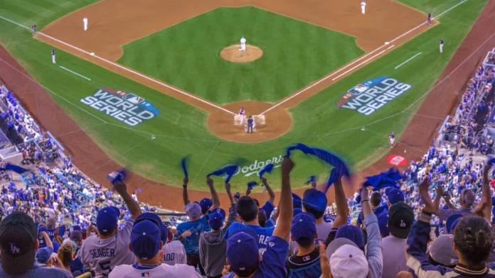 Juichende fans met blauwe shirts en petten zwaaien met vlaggen boven het speelveld tijdens een World Series wedstrijd van de Dodgers