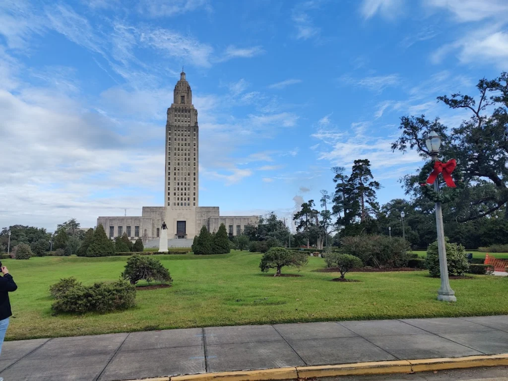De hoge art-decotoren van het Louisiana State Capitol in Baton Rouge, omgeven door een groen park met struiken en bomen