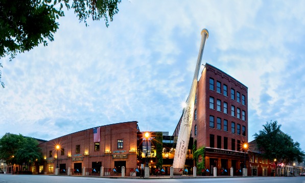 Een enorme honkbalknuppel leunt tegen de bakstenen gevel van het Louisville Slugger Museum in de schemering