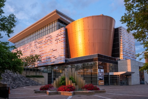 Modern gebouw met een koperkleurige cilindervormige gevel en een fontein op het plein voor het Muhammad Ali Center in Louisville