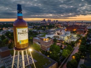 Een watertoren vermomd als een gigantische fles Old Forester bourbon torent boven de skyline van Louisville bij zonsondergang uit