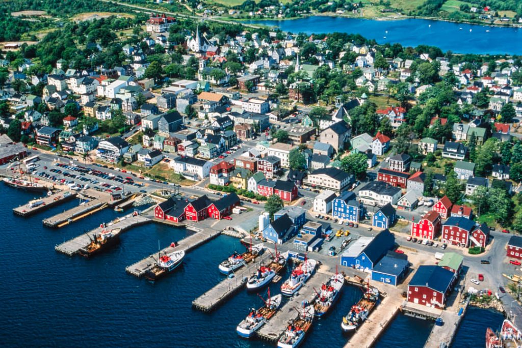 Luchtfoto van Lunenburg met kleurrijke huizen, een kerktoren en vissersboten afgemeerd langs de haven