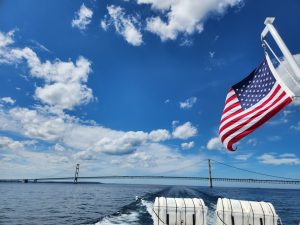 Wapperende Amerikaanse vlag aan een boot met op de achtergrond de hangbrug Mackinac Bridge over het water