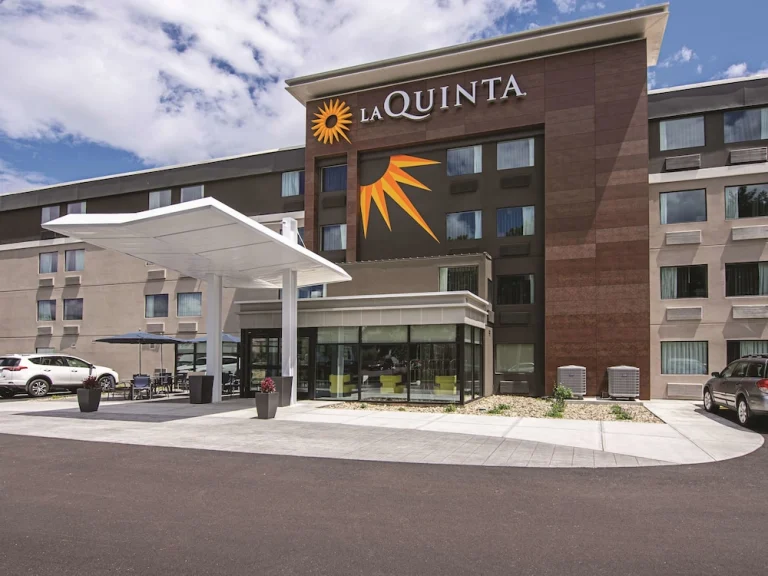Bruin met oranje gevel van een La Quinta hotel met een luifel boven de ingang en geparkeerde auto's ervoor in Maine