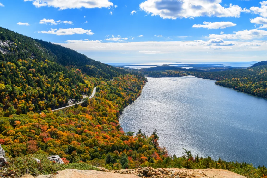 Luchtfoto van een kleurrijk havenstadje met aangemeerde boten en een jachthaven, omringd door bebost heuvelland in Maine
