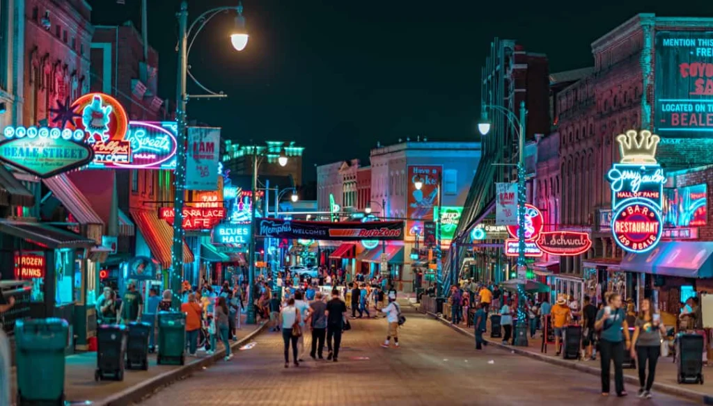 Drukke straat vol wandelaars onder felle neonreclames van bars en restaurants aan Beale Street in Memphis