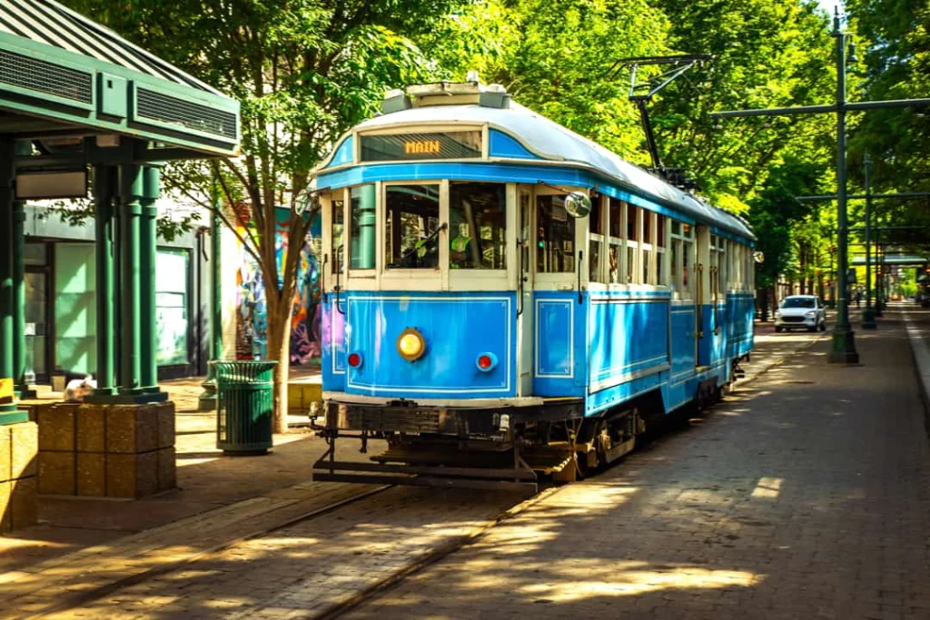 Blauwe en witte historische tram rijdt over de rails van Main Street in Memphis tussen bomen en straatlantaarns door