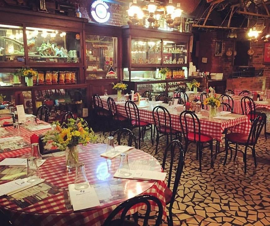 Ronde tafels met roodwit geblokte kleedjes en bloemen in het rustieke interieur van het Rendezvous restaurant in Memphis