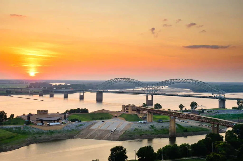 Luchtopname van een grote boogbrug over de Mississippi rivier bij Memphis met een oranje gloeiende avondlucht en de zon net boven de horizon