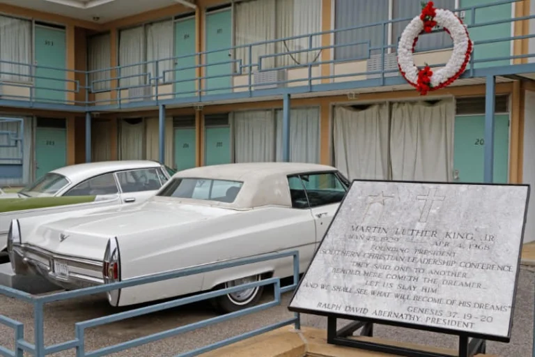 Klassieke witte auto's staan voor het Lorraine Motel in Memphis, met een rouwkrans en gedenkplaat ter nagedachtenis aan Martin Luther King
