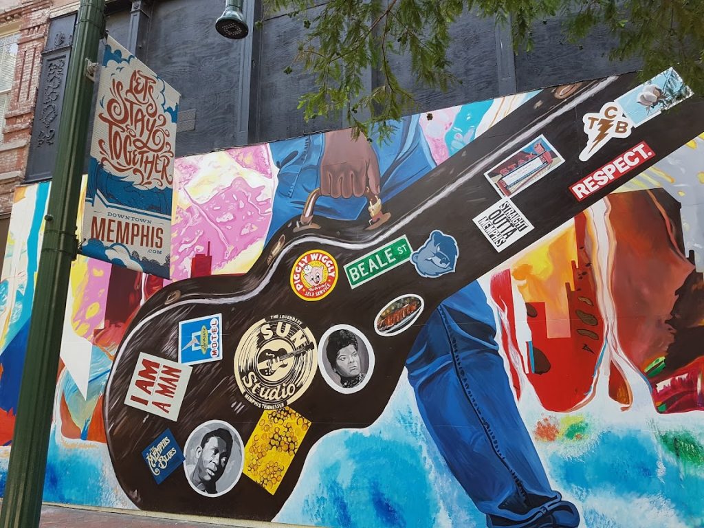 Grote muurschildering in de vorm van een gitaar bedekt met stickers van Memphis attracties zoals Sun Studio en Beale Street