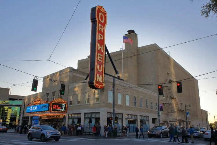 Straatbeeld van het Orpheum Theatre in Memphis met verlichte neonreclame en voetgangers die oversteken bij schemering