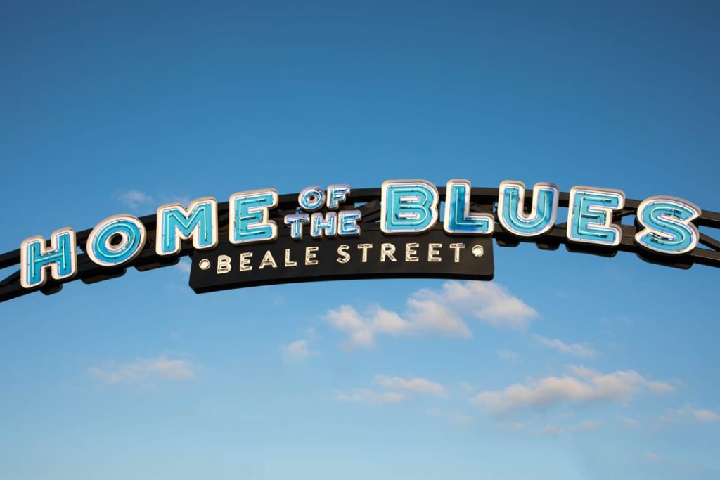 Booggevormd bord met de tekst Home of the Blues Beale Street in lichtblauwe letters tegen een heldere blauwe lucht