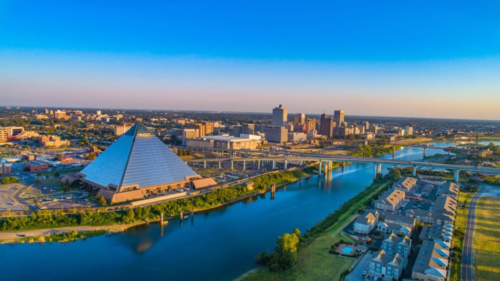 Luchtfoto bij zonsondergang van de skyline van Memphis met de glazen piramide, een brug over de rivier en woonwijken op de voorgrond