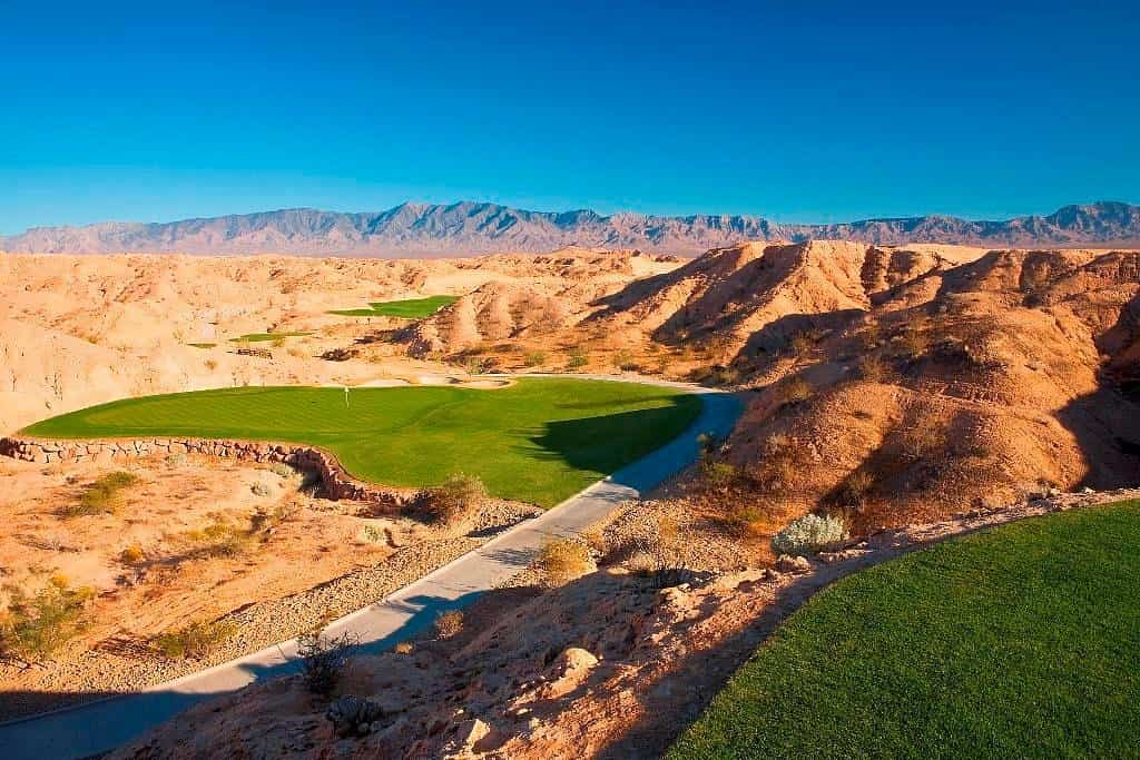 Luchtfoto van een groene golfbaan met kunstmatig meertje te midden van rode rotsheuvels en bergen bij Mesquite, Nevada