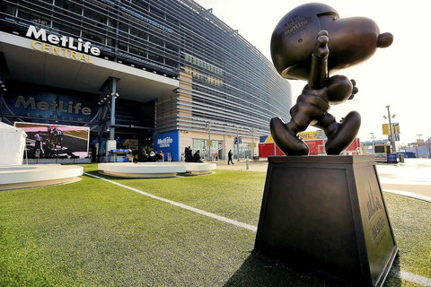 Een groot bronzen standbeeld van Snoopy staat op het plein voor het MetLife Stadium onder een heldere lucht
