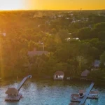 Luchtfoto van meerdere steigers die uitsteken in een lagune terwijl de zon oranje onder gaat bij Bacalar