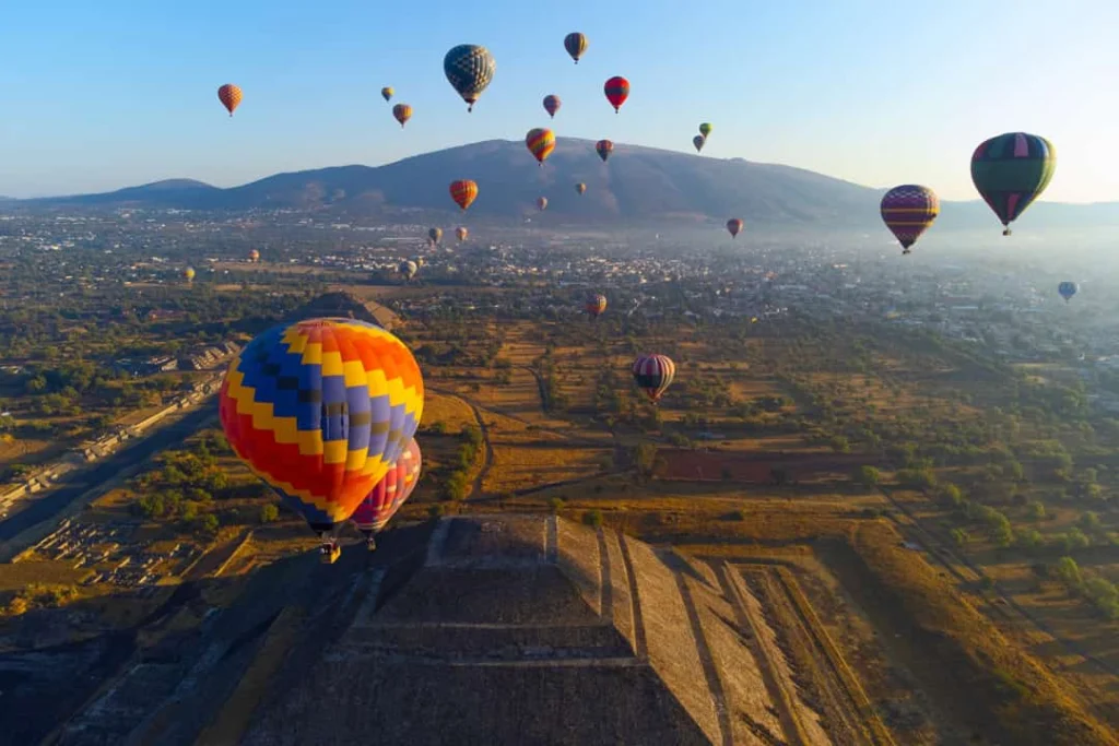 Tientallen kleurrijke heteluchtballonnen zweven in de ochtend boven de piramide van de zon bij Teotihuacan