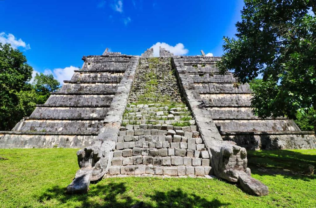 De stenen trappen van de piramide van Kukulcán met slangenkoppen aan de voet in Chichén Itzá op een zonnige dag