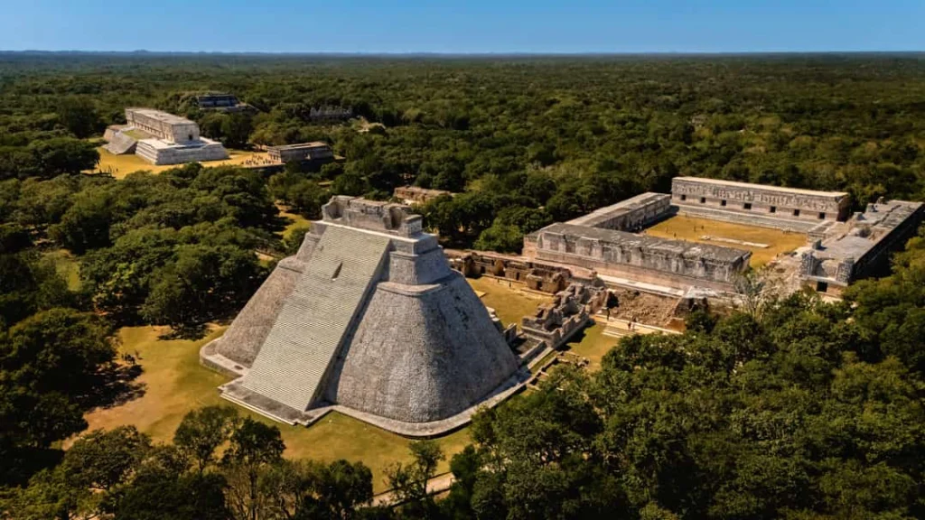 Luchtfoto van de piramide van de tovenaar en omliggende Maya gebouwen omringd door dicht groen bij Uxmal