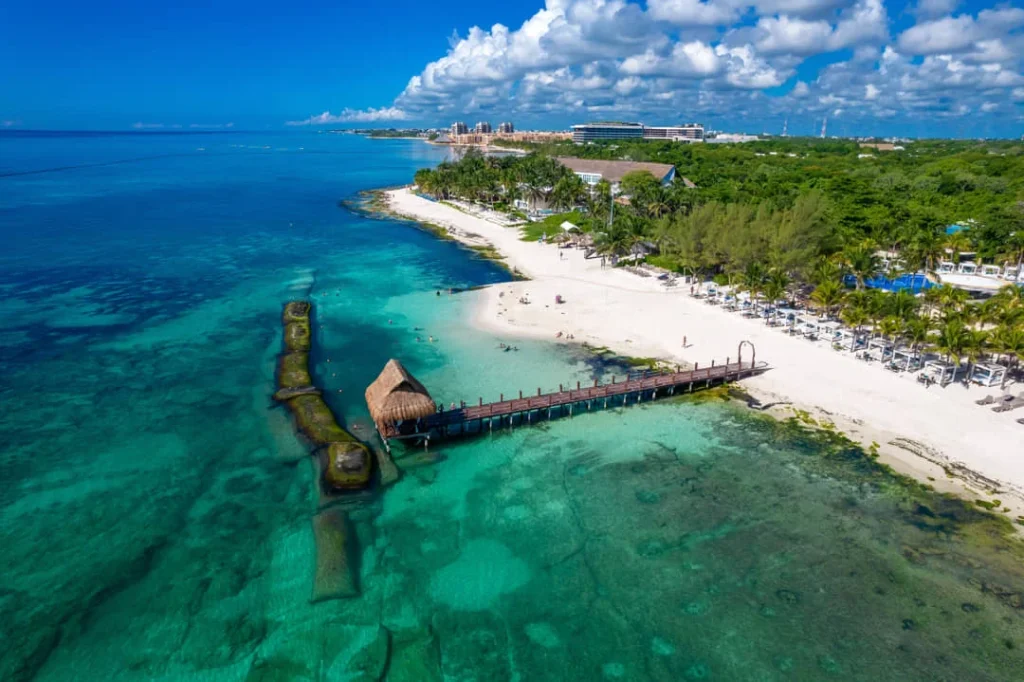 Luchtfoto van een wit zandstrand met een houten steiger die uitsteekt in helder turquoise water in Playa del Carmen
