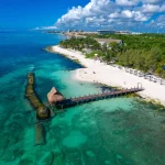 Luchtfoto van een wit zandstrand met een houten steiger die uitsteekt in helder turquoise water in Playa del Carmen