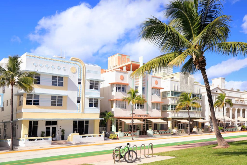 Pastelkleurige art deco hotels met ronde balkons langs Ocean Drive in Miami Beach met palmbomen en een fiets