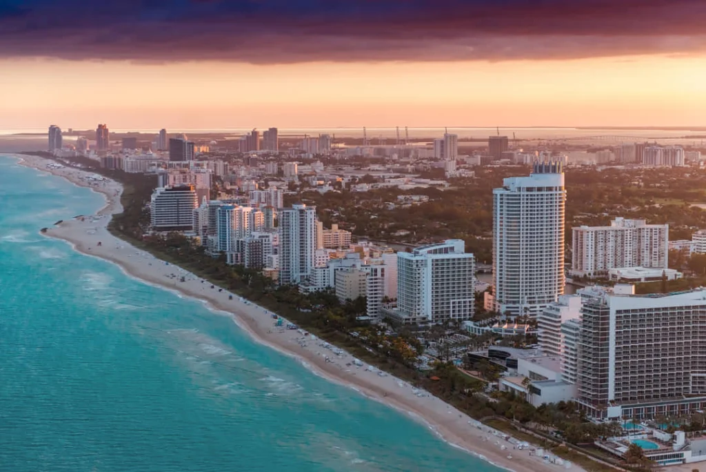 Luchtfoto van hotels en appartementengebouwen langs het strand van Miami Beach met de kustlijn in warm avondlicht