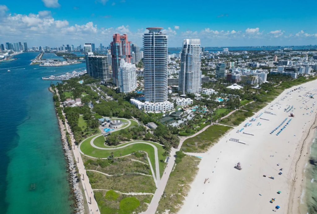 Luchtfoto van een groen park met slingerend pad naast wolkenkrabbers, een strand en de blauwe zee in Miami Beach