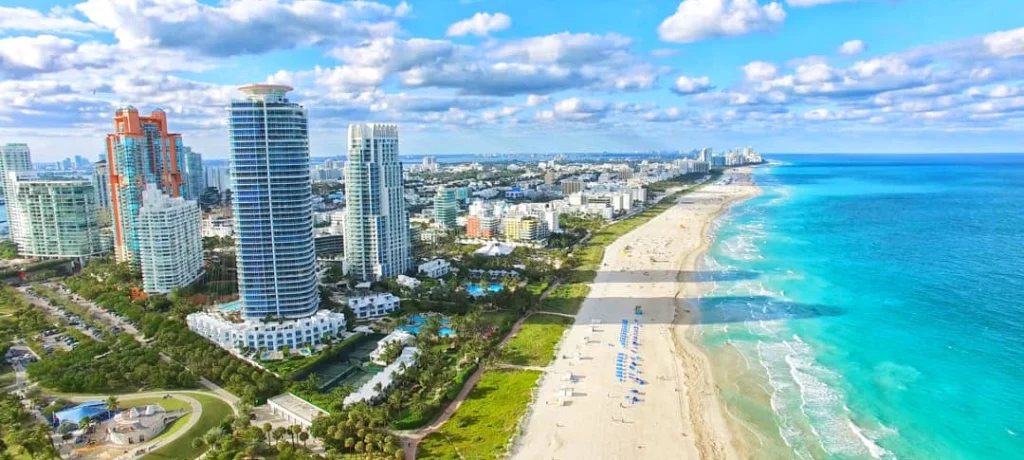 Luchtfoto van de kustlijn van Miami Beach met wolkenkrabbers, een breed wit strand en helderblauw water van de Atlantische Oceaan