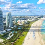 Luchtfoto van de kustlijn van Miami Beach met wolkenkrabbers, een breed wit strand en helderblauw water van de Atlantische Oceaan