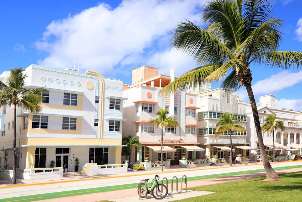 Pastelkleurige art deco gebouwen aan Ocean Drive in Miami Beach met palmbomen, terrasjes en een fiets tegen een rek op straat