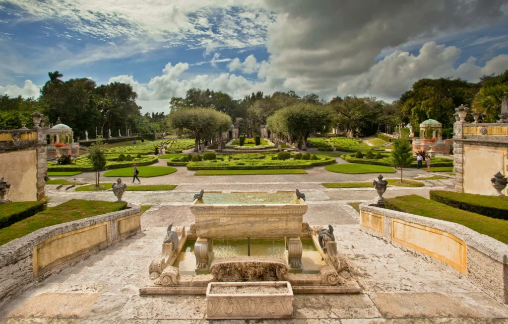 Stenen fontein op een terras met uitzicht over symmetrisch aangelegde tuinen met heggen en bomen bij Vizcaya in Miami