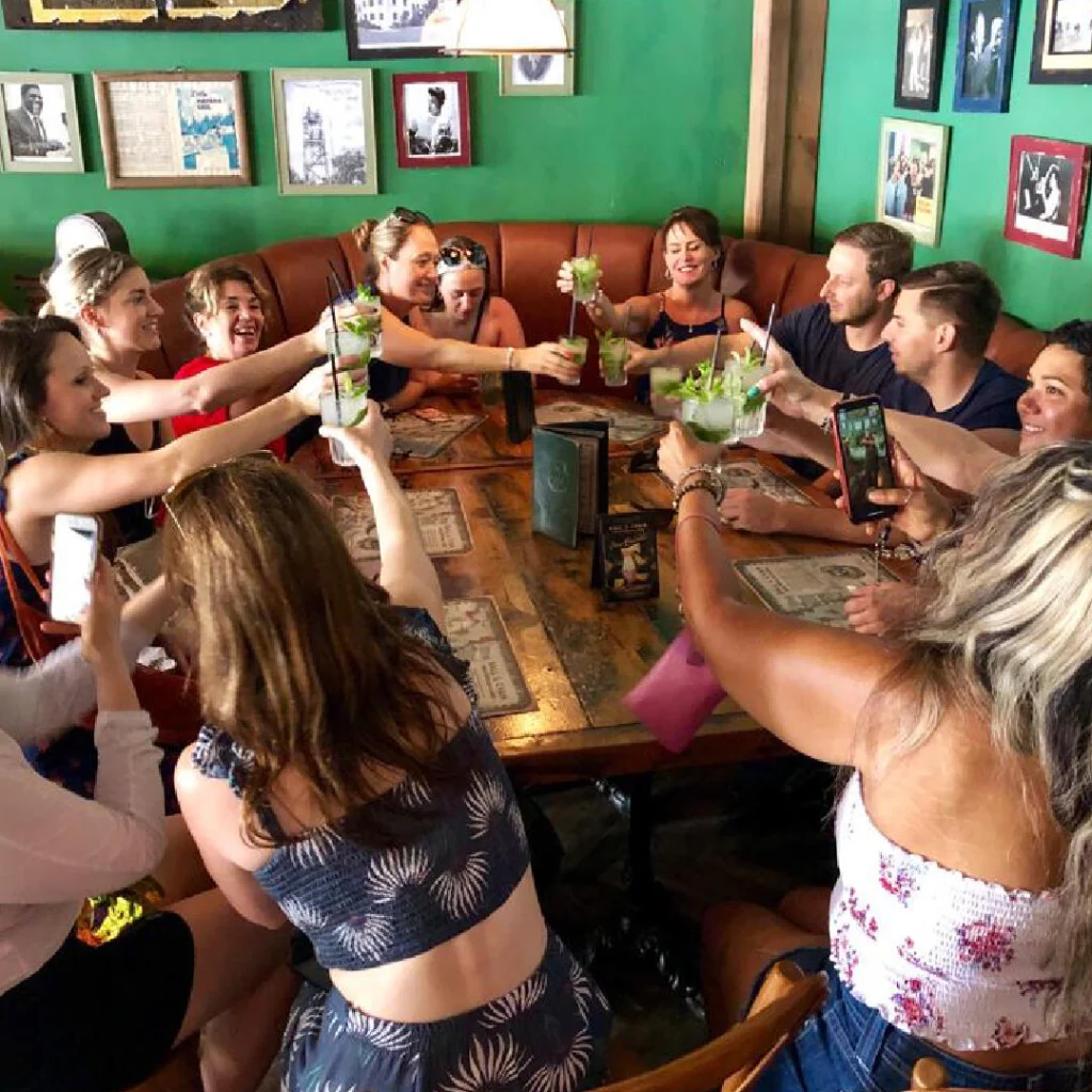 Een groep reizigers heft in een groen ingericht restaurant in Little Havana Miami samen glazen mojito voor een toost