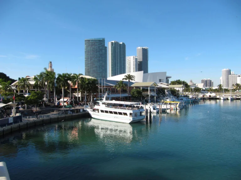 Een witte rondvaartboot en jachten liggen afgemeerd in de jachthaven bij Bayside Marketplace in Miami, met de wolkenkrabbers van downtown op de achtergrond