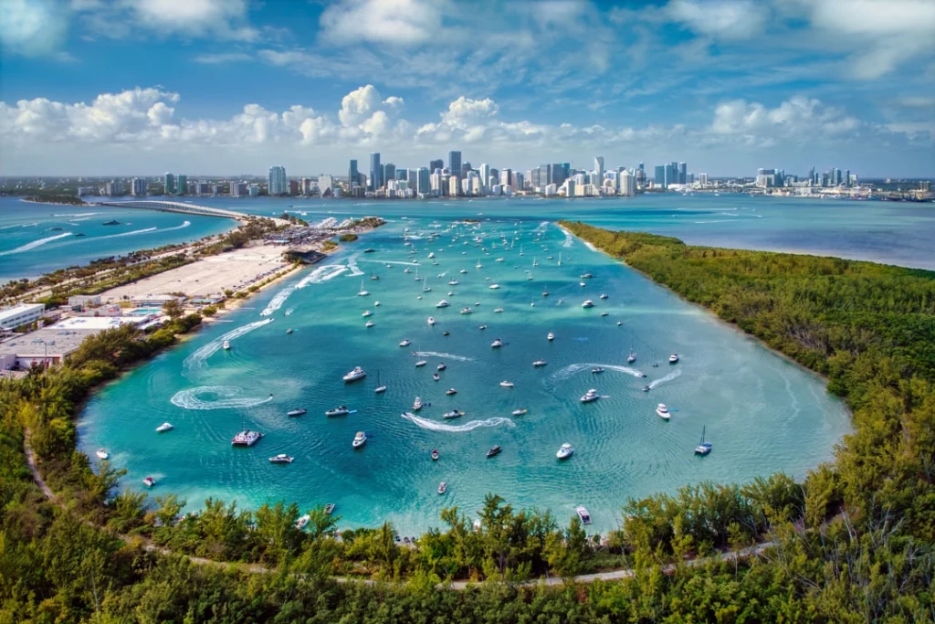 Luchtfoto van een turquoise baai vol ankerende boten met op de achtergrond de wolkenkrabbers van Miami, Florida