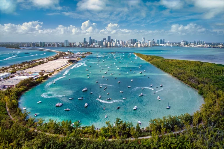Luchtfoto van een turquoise baai vol ankerende boten met op de achtergrond de wolkenkrabbers van Miami, Florida