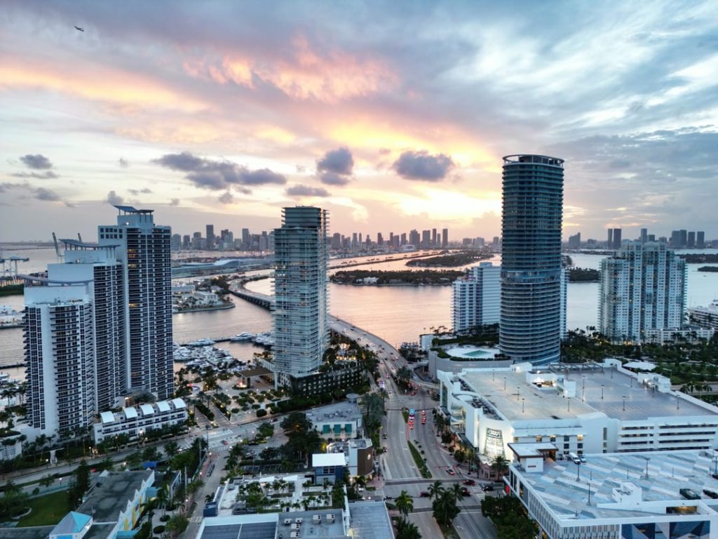 Luchtfoto van wolkenkrabbers langs het water met jachten en een brug bij een kleurrijke zonsondergang in Miami