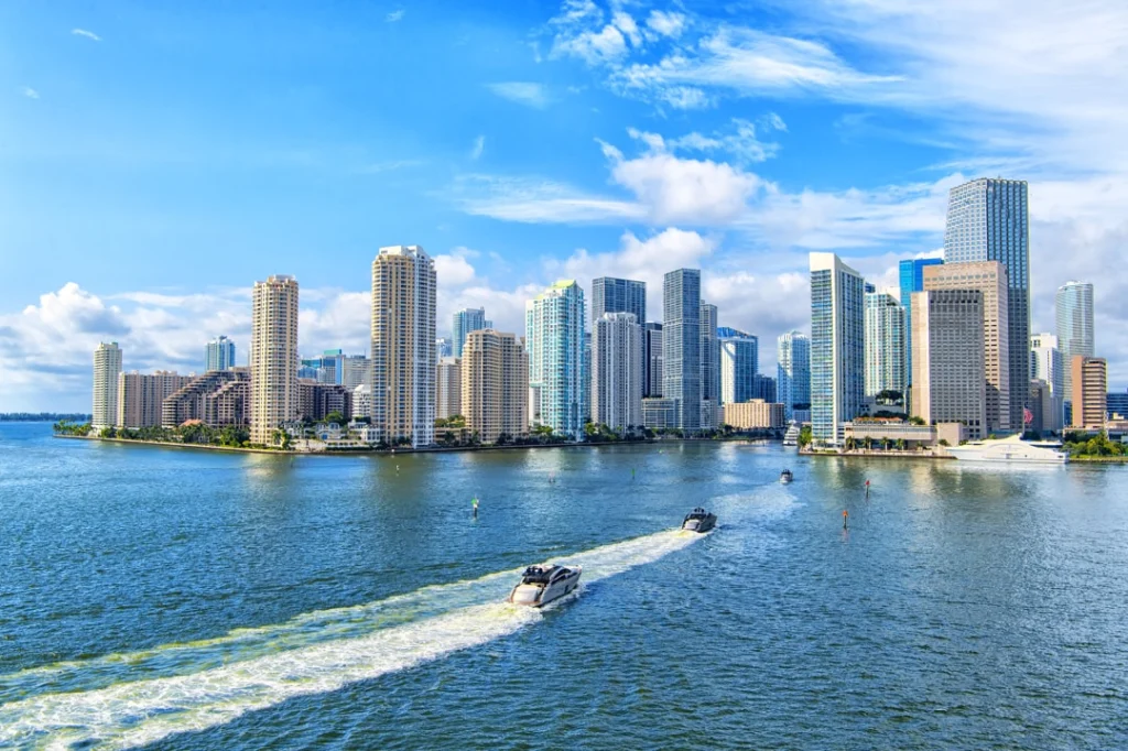 Wolkenkrabbers van de skyline van Miami aan het water met twee speedboten die een schuimspoor achterlaten op de baai