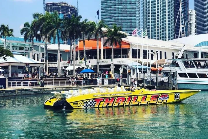 Felgele Thriller-speedboot ligt aangemeerd bij de jachthaven in Miami met palmbomen en wolkenkrabbers op de achtergrond