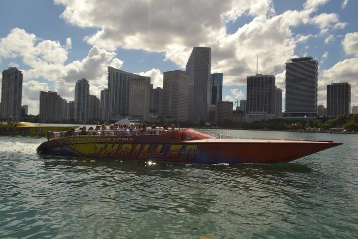 Een fel gekleurde speedboot met opschrift Thriller vaart over het water voor de wolkenkrabbers van Miami