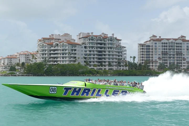 Een groene speedboot met toeristen aan boord maakt hoge vaart op het turquoise water voor de skyline van appartementengebouwen in Miami