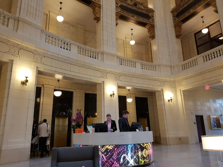 Ruime hotellobby met sierlijke witte pilaren, hoge plafonds en een balie waar medewerkers gasten helpen in Michigan